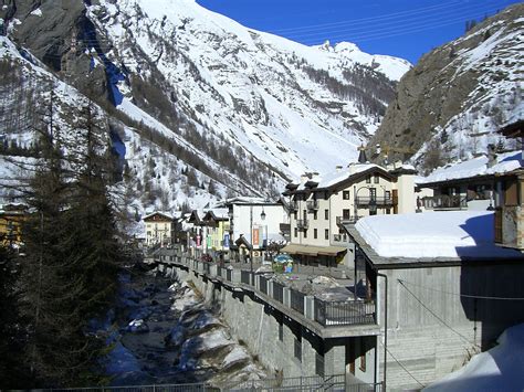 snow covered mountains and buildings in the foreground, with a river ...