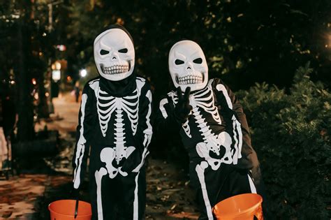 Unrecognizable persons in skeleton costumes on street · Free Stock Photo