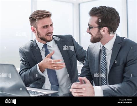 two businessmen talking, sitting at his Desk Stock Photo - Alamy