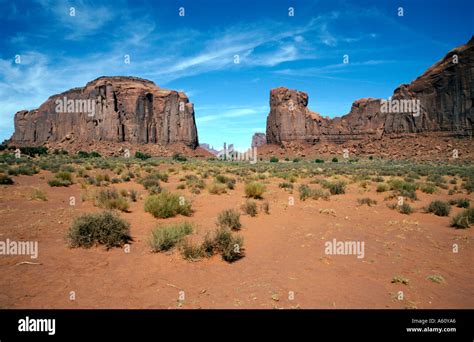 SAndstone Buttes rising above the orange red sands of the desert floor of Monument Valley on the ...