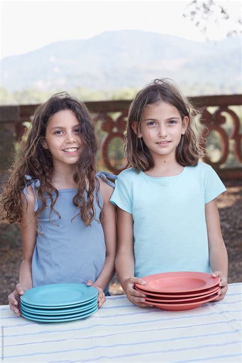 "Two Young Girls Setting An Open Air Table For A Party" by Stocksy Contributor "Miquel Llonch ...