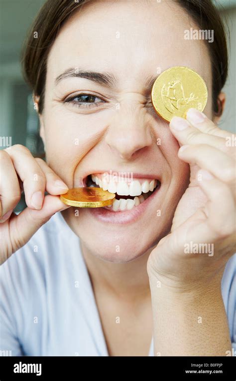 Amusing woman bites into gold coins Stock Photo - Alamy