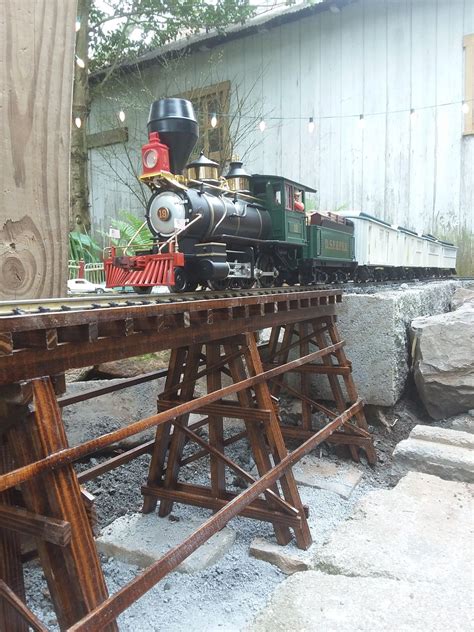 an old fashioned train is on display in front of a wooden structure and tree stumps