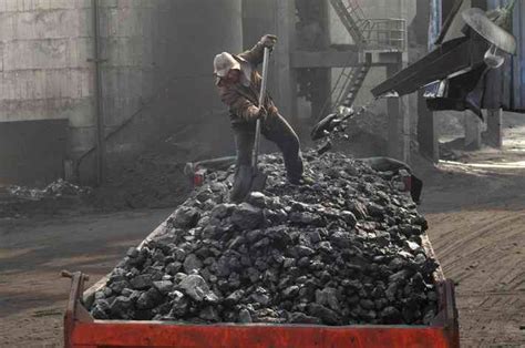 A labourer loads coal onto a truck at Sanyuan Coal Mine in Changzhi, Shanxi province, China ...