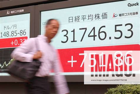 October 10, 2023, Tokyo, Japan - A pedestrian passes before a share prices board in Tokyo on