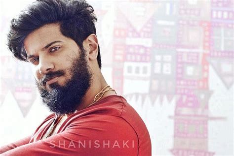 a man with a beard and red shirt in front of a colorful wallpapered ...