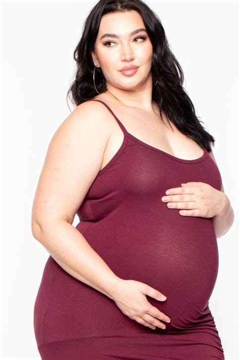 This plus-size maternity stretch knit dress features a scoop neckline, adjustable cami straps ...