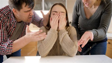 Adolescente llorando y cerrando la cara con las manos después del conflicto con los padres ...