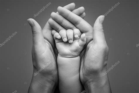 Newborn baby hand holding in mother hands isolated on grey background ...