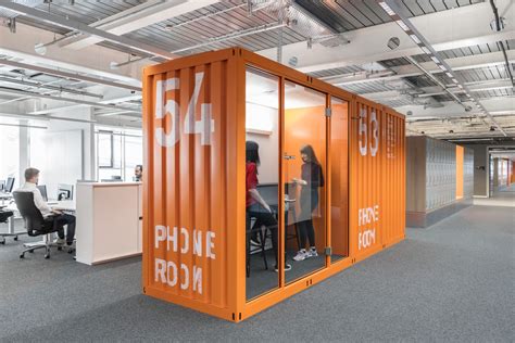 an office with orange shipping containers and people working in the ...