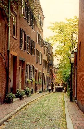 an alley way with brick buildings and green trees on both sides ...