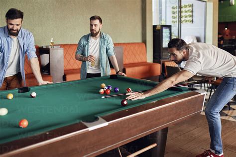 Friends playing billiards together stock photo