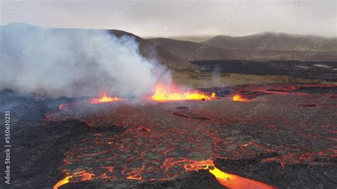 Volcano vent eruption with ejected lava river flowing down valley in ...