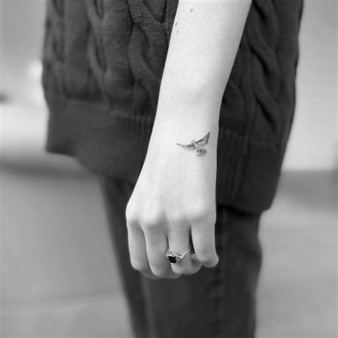 Tiny dove tattoo placed on the hand.