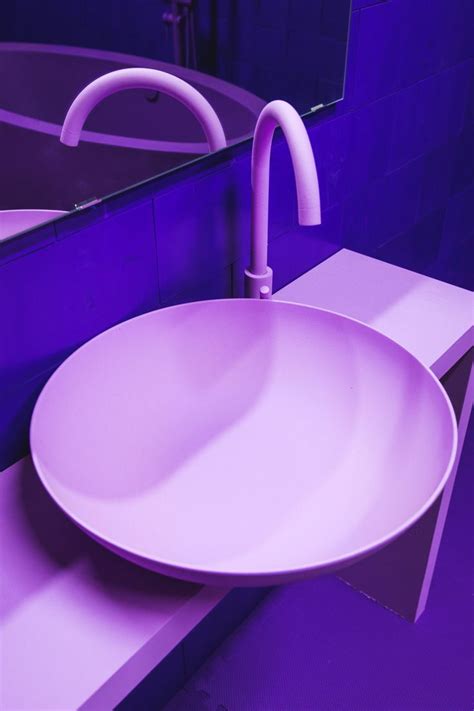 a white sink sitting on top of a counter next to a purple wall mounted ...