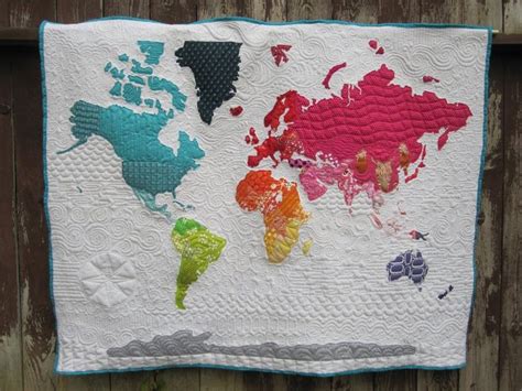 a quilted world map hanging on the side of a wooden fence with colorful ...