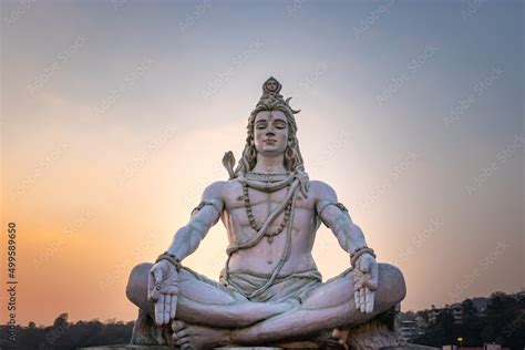 hindu god lord shiva statue in meditation posture with dramatic sky at evening from unique angle ...