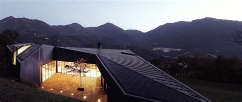 a house that is lit up with lights on the roof and in front of some mountains