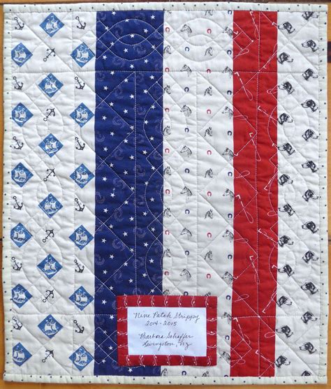 a red, white and blue quilted wall hanging with a name tag on it