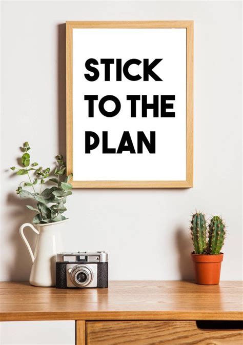 a wooden table topped with a potted plant next to a framed poster that ...