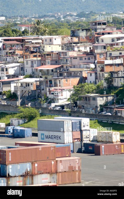 Cars and containers at the docks at Barbados with slums' right behind ...