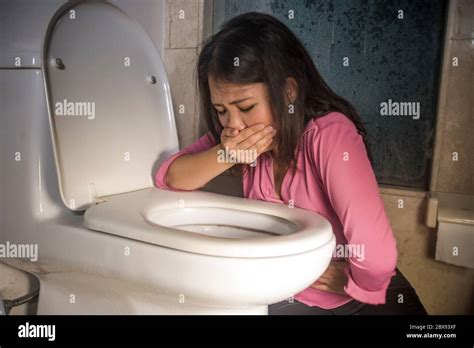 young drunk or pregnant Asian woman vomiting and throwing up in toilet WC feeling unwell and ...