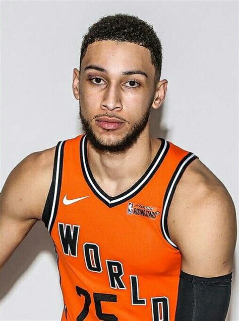 a man in an orange basketball jersey is posing for a photo with his hands on his hips