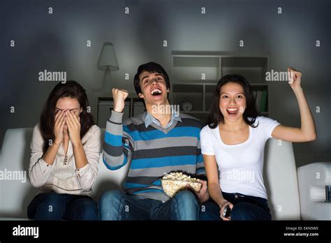 group of young people watching TV on the couch Stock Photo - Alamy