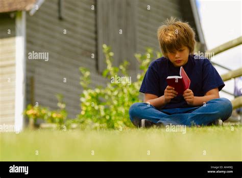 Boy reading a book outside Stock Photo - Alamy