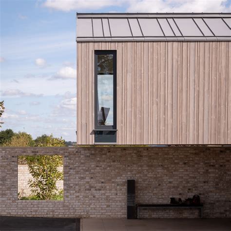 Weathered timber cladding covers shed-like house in rural England A cantilevered upper floor and ...