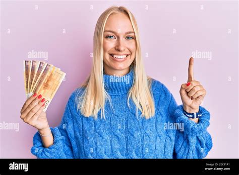 Young blonde girl holding 100 norwegian krone banknotes smiling with an ...