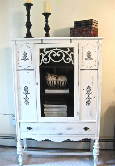 a white cabinet with some books on top of it and a candle in the corner