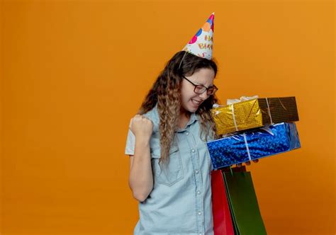 Free Photo | With closed eyes joyful young girl wearing glasses and birthday cap holding gift boxes