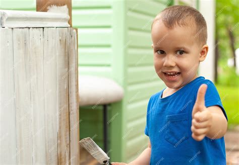 Premium Photo | Little smiling kid boy painting wooden furniture with ...