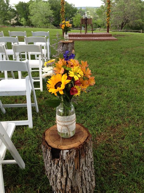 aisle markers of tree stumps with mason jars of flowers | Rustic ...