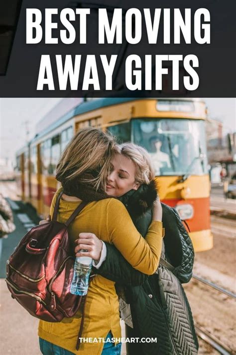 Two women embrace at a train station in front of a yellow train, with ...