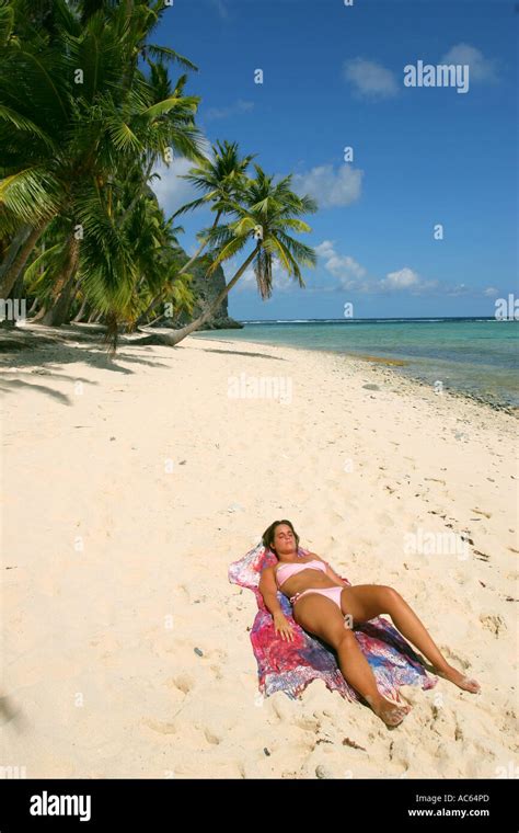 YOUNG WOMAN SUNBATH SUNBATHING IN A TROPICAL BEACH A young woman taking ...