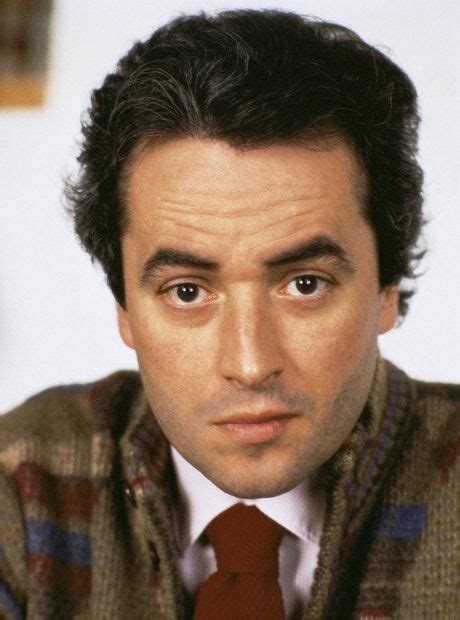 a man in a sweater and tie looking at the camera with an intense look on his face