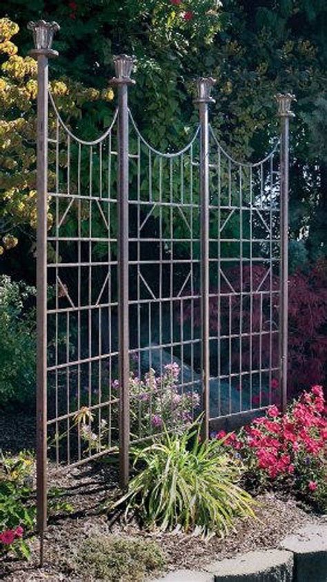 an iron garden fence surrounded by flowers and trees