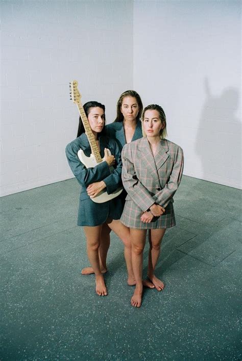 three women standing in front of a wall with an electric guitar on ...