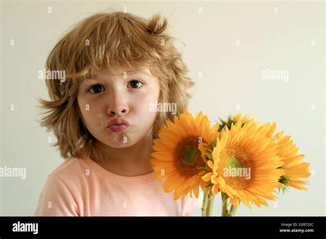 Funny face of son child with bouquet of sunflower flowers. Spring ...