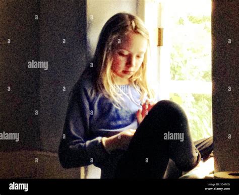 Girl reading in window light Stock Photo - Alamy