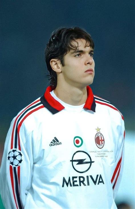 a young man standing in front of a soccer ball wearing a white and red shirt