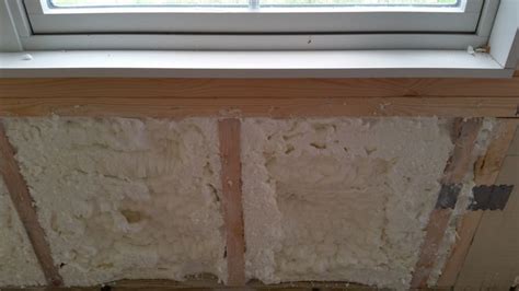 an unfinished window sill with insulation on the outside and in the inside, as seen from below