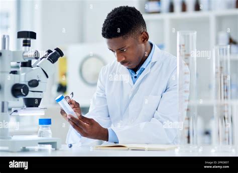 Is this the right stuff. a focused young male scientist writing labels ...