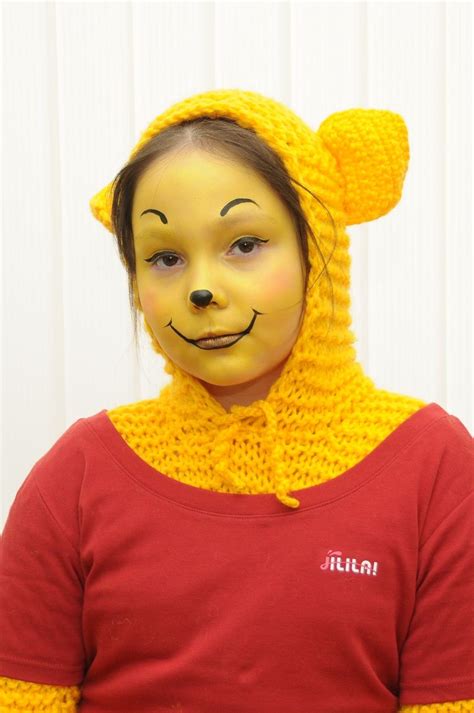 a woman wearing a yellow bear costume with her face painted like a teddybear