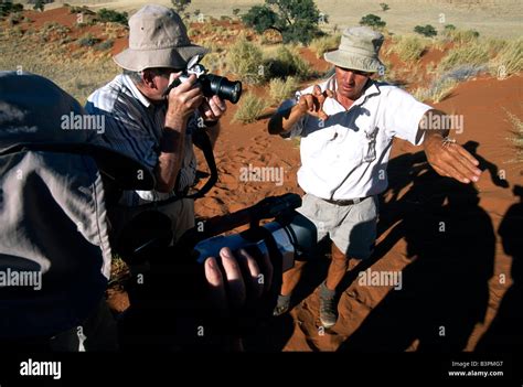 Man holding white spider in his hand photographed by tourists, Tok Tokkie Trail, NamibRand ...