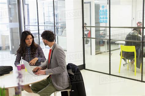 Business people talking, using laptop in office meeting - Stock Photo - Dissolve