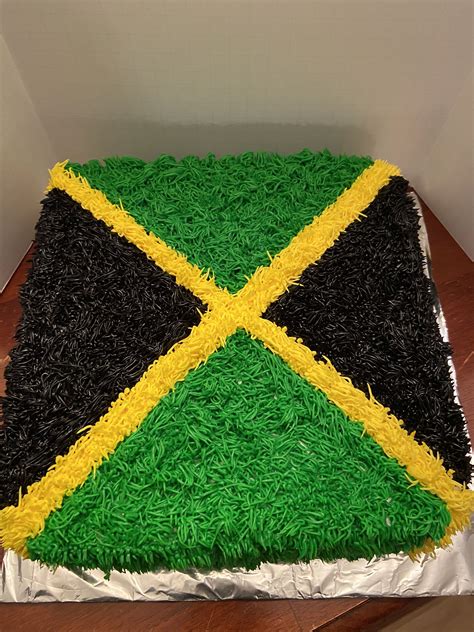 a cake that is decorated with grass and black, yellow and green stripes on it