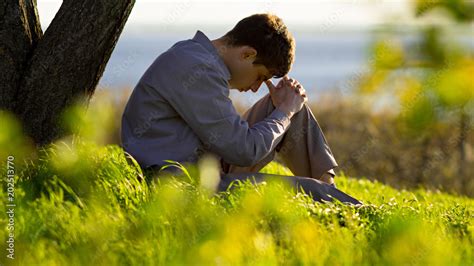 young man praying to God in the nature bowing his head to his knees, concept religion foto de ...